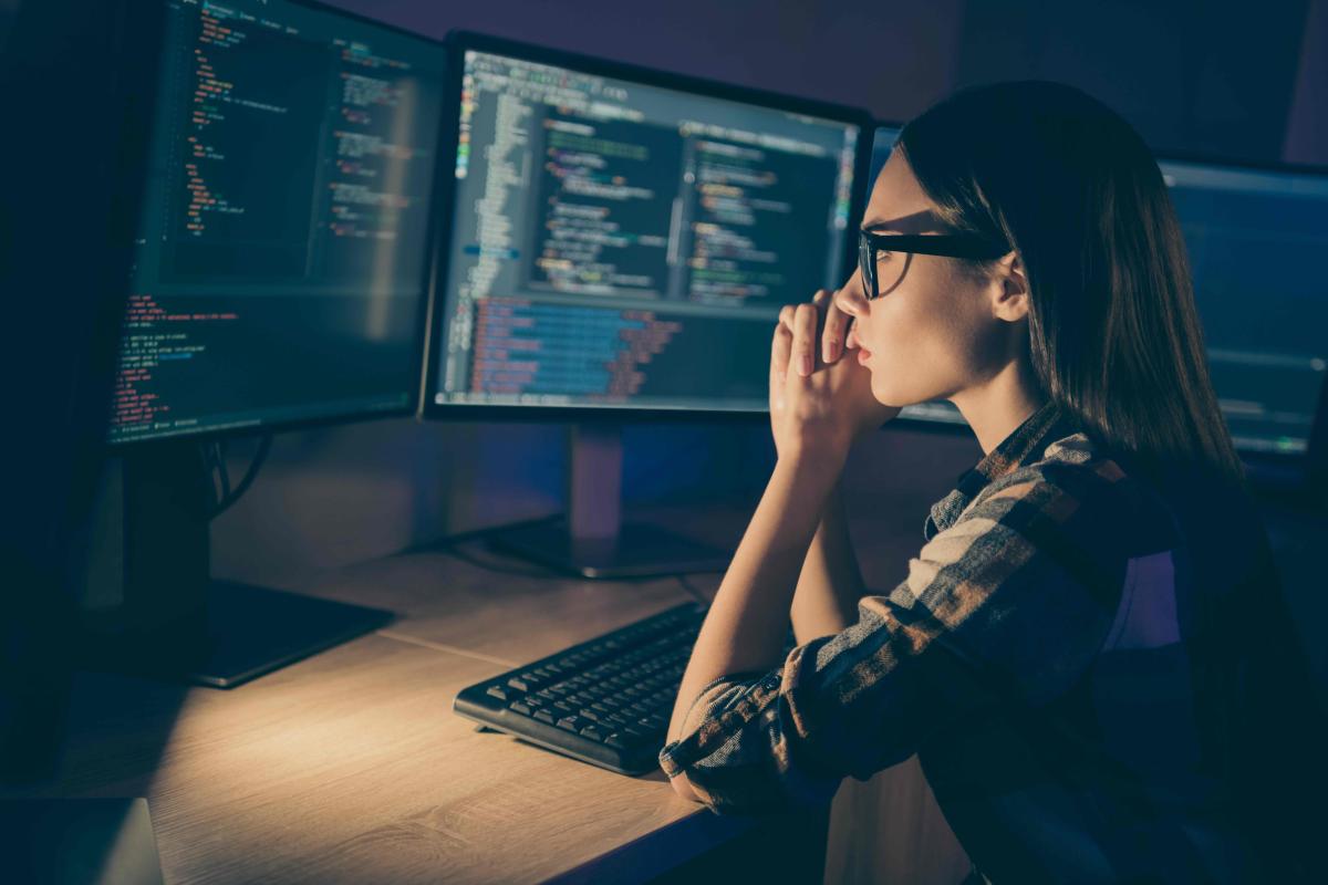 Female programmer staring at software code on a computer monitor 