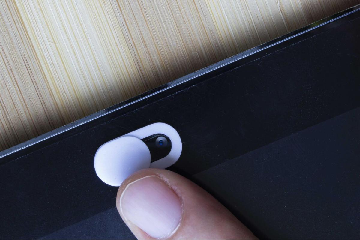 A fingertip about to close a webcam cover