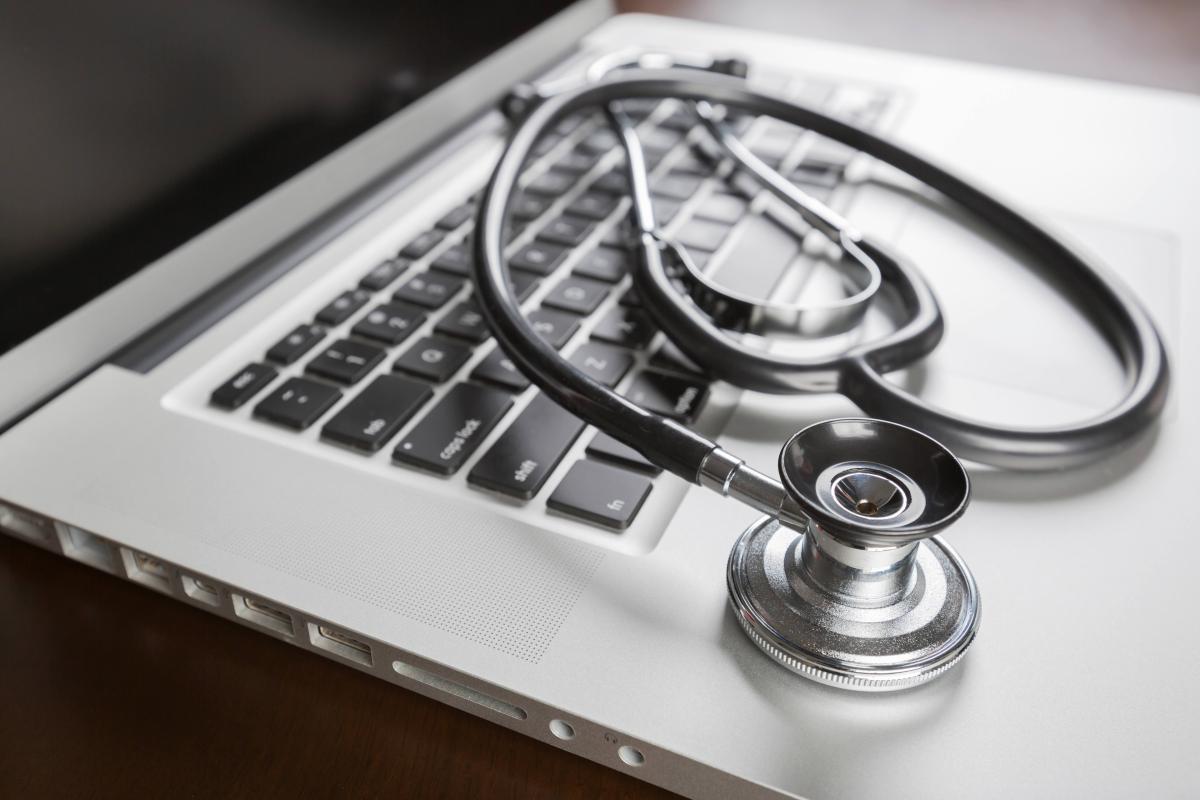 A stethoscope lying on the keyboard of an open laptop computer